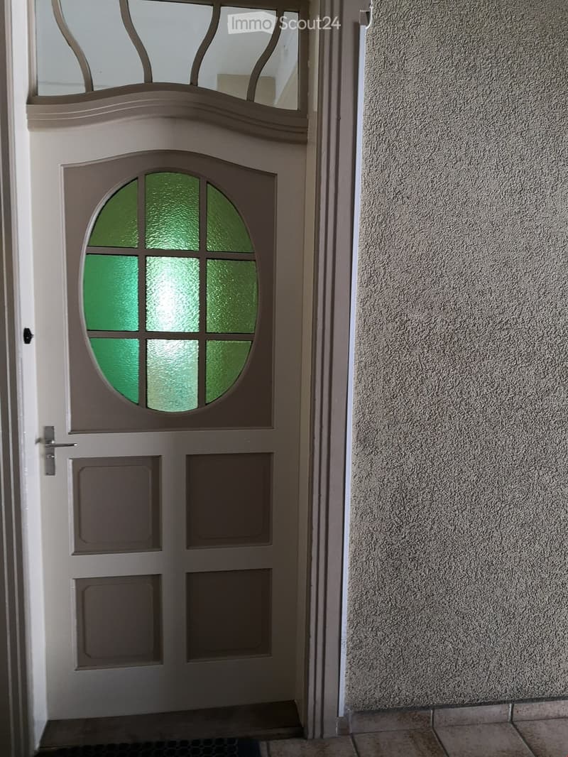 {"visible_features": ["Raised ground floor"],    "type": "Entrance",    "description": "White door with green oval window, mounted on a raised ground floor.",    "localized_descriptions":        {        "EN": "White door with green oval window, moun