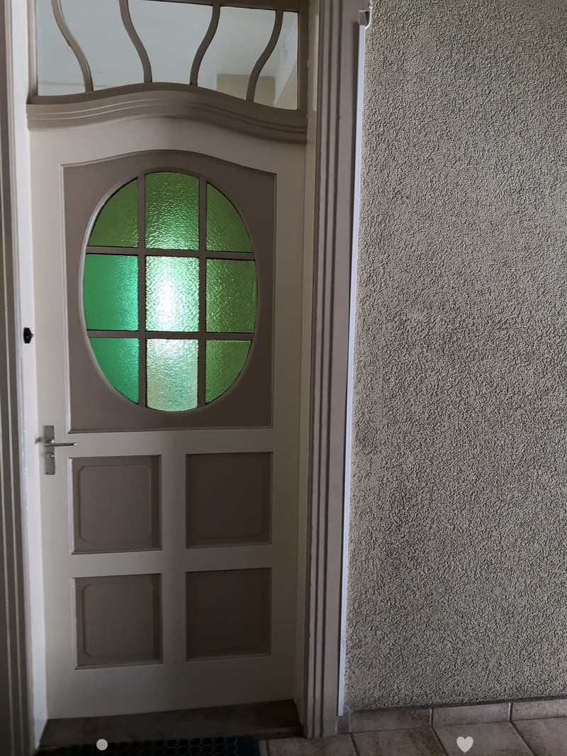 {"visible_features": ["Raised ground floor"],    "type": "Entrance",    "description": "White door with green oval window, mounted on a raised ground floor.",    "localized_descriptions":        {        "EN": "White door with green oval window, moun
