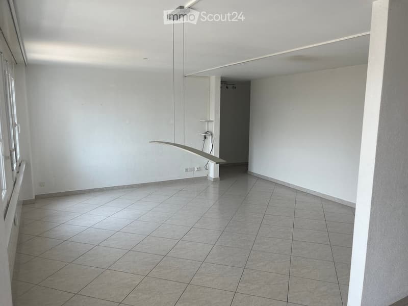 Empty hallway with tiled floor, white walls, and a modern light fixture on the ceiling.