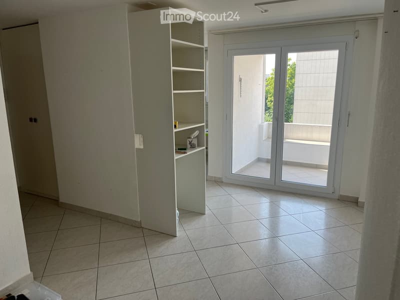 Empty room with tiled floor, white walls, and a sliding glass door leading to a balcony.