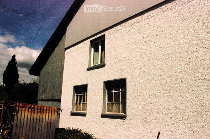 White exterior building with multiple windows and a sloped roof.