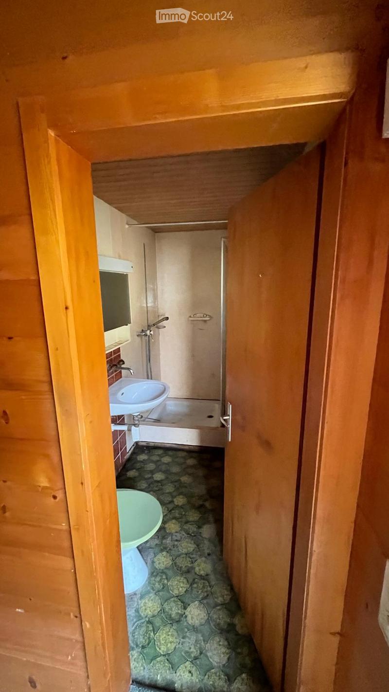 Small bathroom with a sink, toilet, and mirror. The floor has a stone tile pattern, and the walls are painted in a light color.