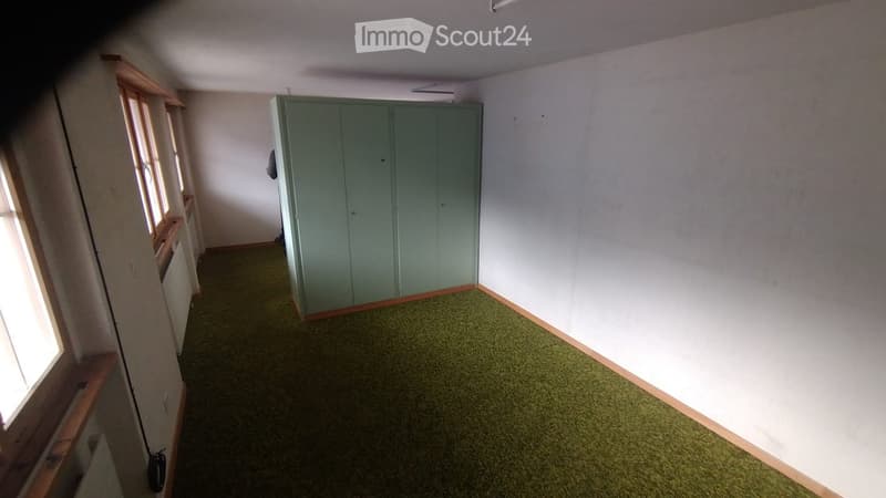 Empty room with light green carpeting, white walls, and a built-in wardrobe. The room has wooden trim around the windows and baseboards.