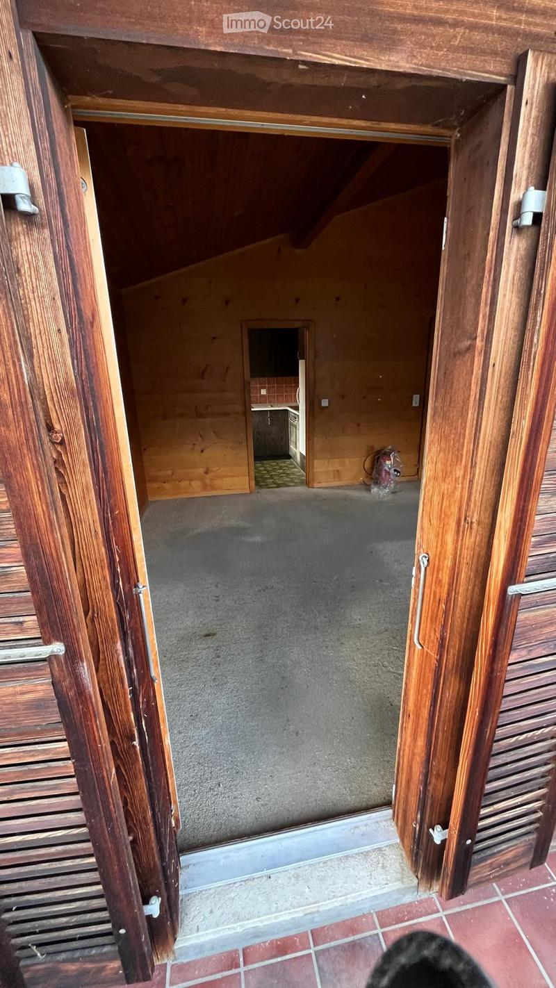 Open wooden-framed corridor leading to a small kitchen area with basic fixtures and a fire extinguisher visible.
