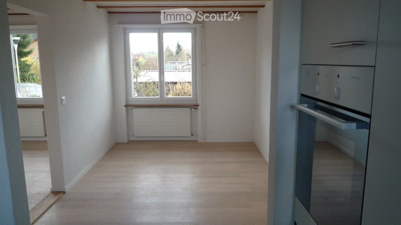 Empty room with light wooden flooring, white walls, and large windows. No furniture or equipment present.