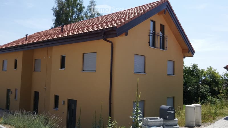Two-story house with yellow exterior, red-tiled roof, multiple windows with blinds, and a small balcony on the upper floor.
