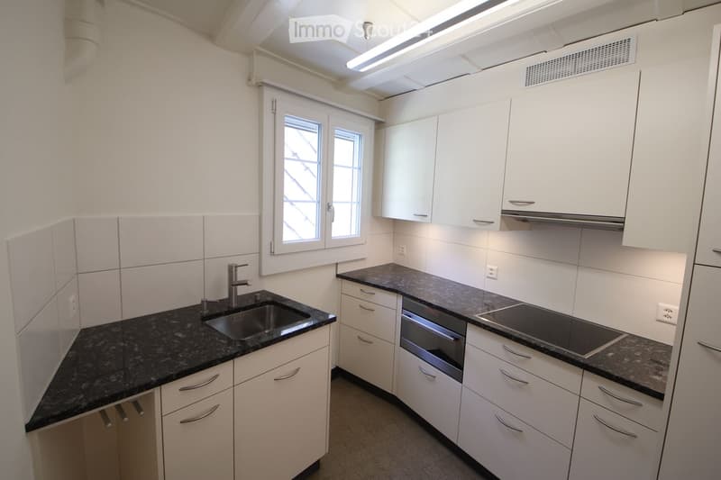 Modern kitchen with white cabinets, black granite countertops, a sink, an oven, and an induction stove.
