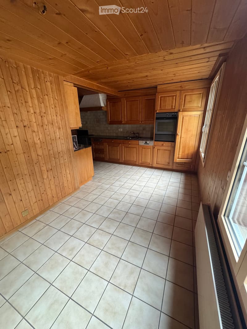 Bright kitchen with wooden cabinets, tiled floor, and stainless steel appliances including an oven and sink.