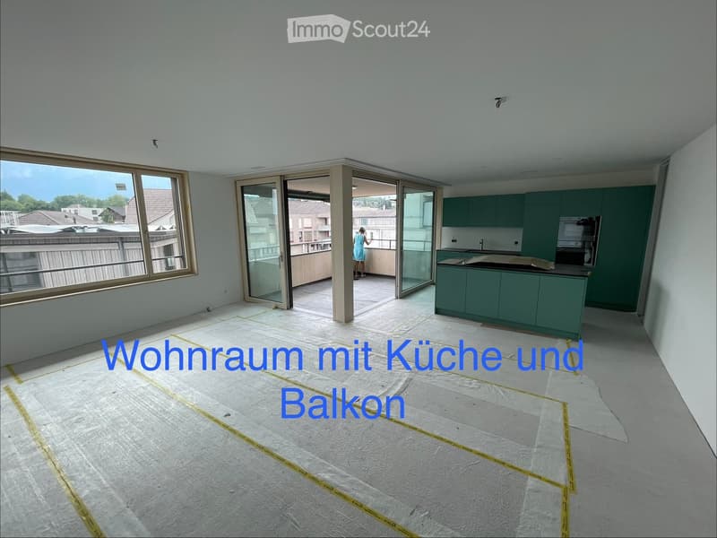 Open-plan living and kitchen area with green cabinets, sink, oven, and access to a balcony.