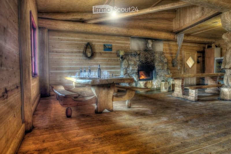 Cozy wooden living room with a stone fireplace, wooden table, benches, and a mirror on the wall.