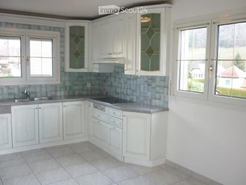 Bright kitchen with white cabinets, stainless steel sink, dishwasher, and tiled backsplash.