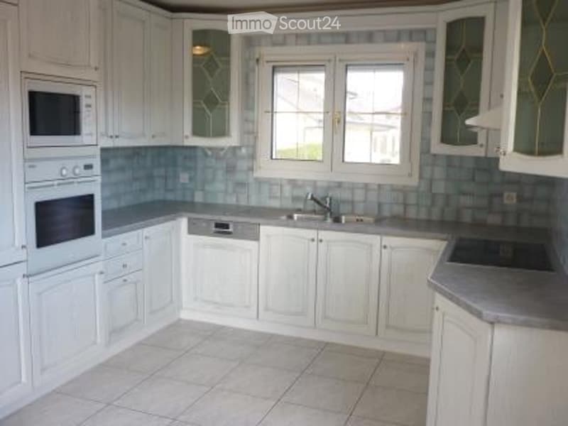 Bright kitchen with white cabinets, stainless steel appliances, and a tiled backsplash.