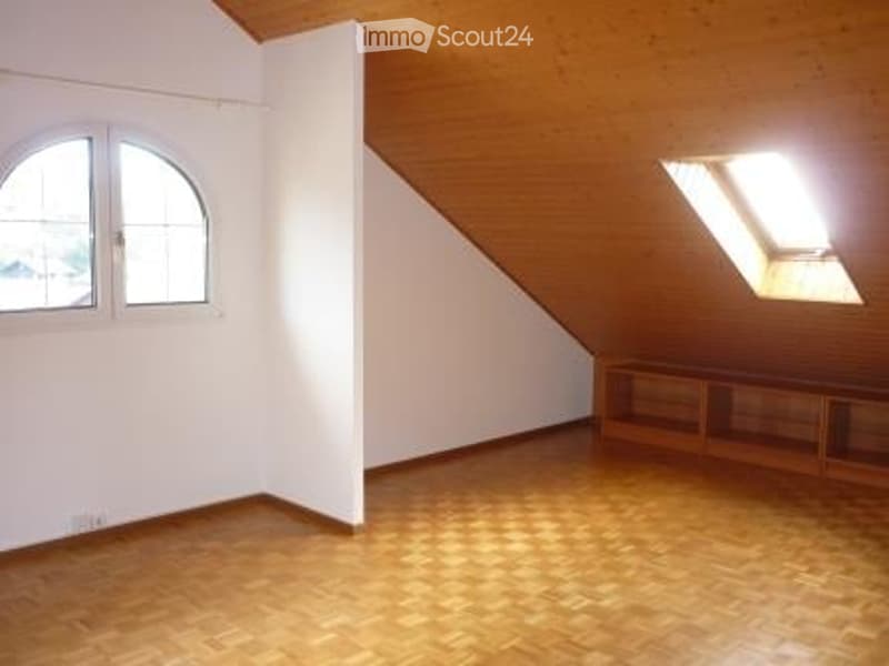 Empty attic room with wooden floor, white walls, and skylight window. No furniture or equipment present.