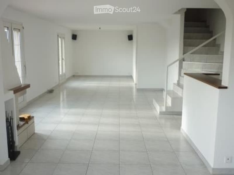 Empty room with white walls, tiled floor, and a staircase leading to an upper level. No furniture or equipment visible.