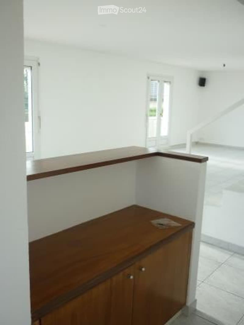 Empty room with white walls, wooden floor, and a small wooden cabinet with a countertop. No furniture or equipment visible.