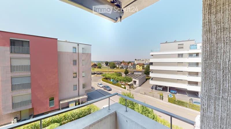Balcony overlooking a modern residential area with several apartment buildings, a parking lot, and a clear view of the surrounding neighborhood.