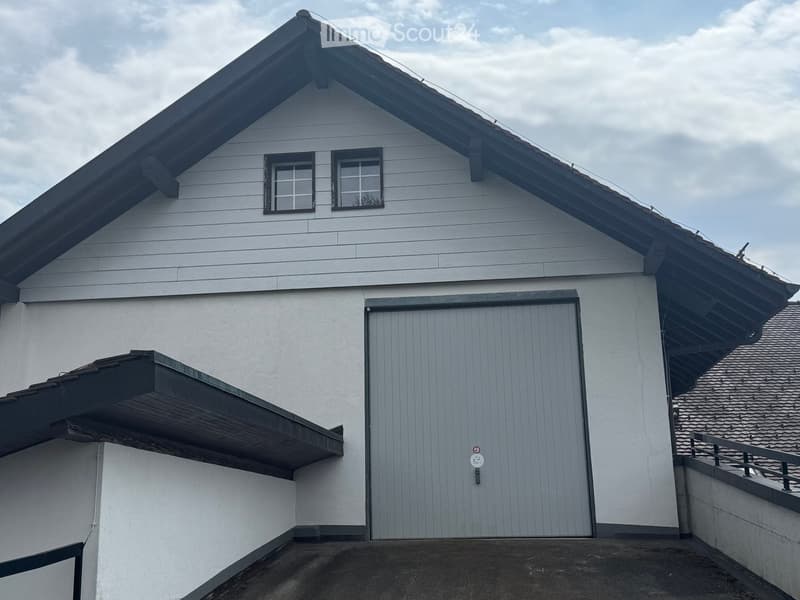 Two-story house with white siding, dark roof, garage door, and small balcony on the left side.