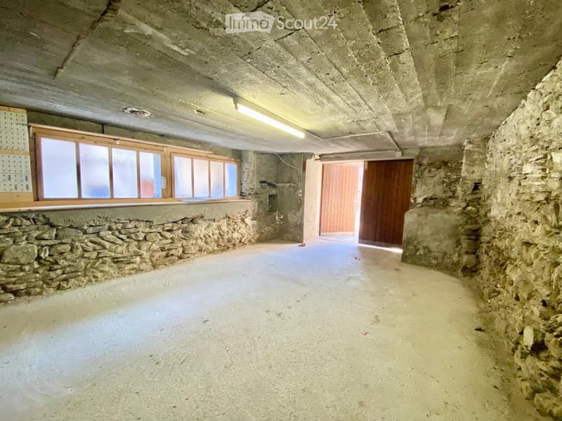 Empty room with stone walls, concrete ceiling, and large windows. No furniture or equipment present.