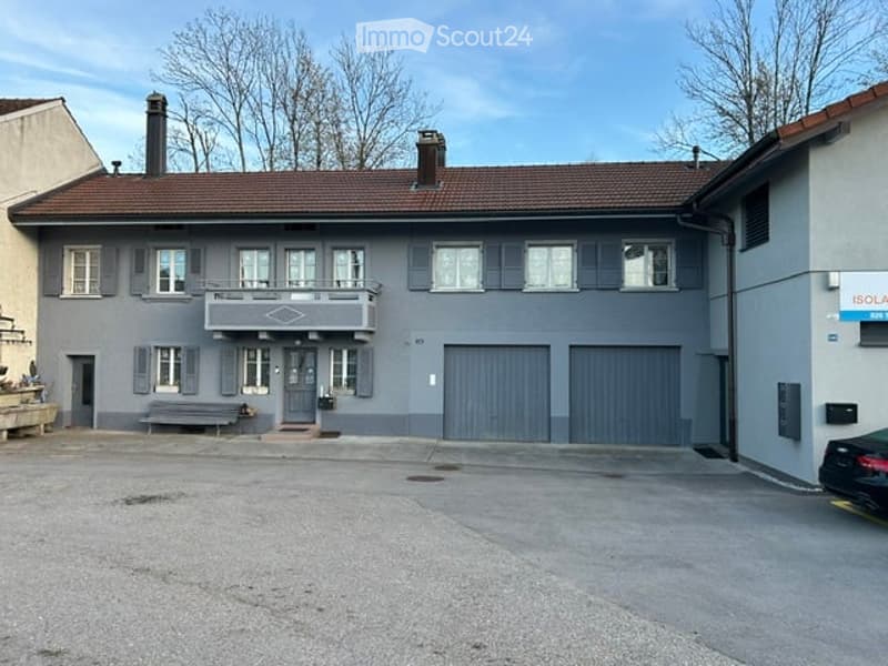 2 story house, gray exterior, brown roof, 2 garages, balcony, bench in front