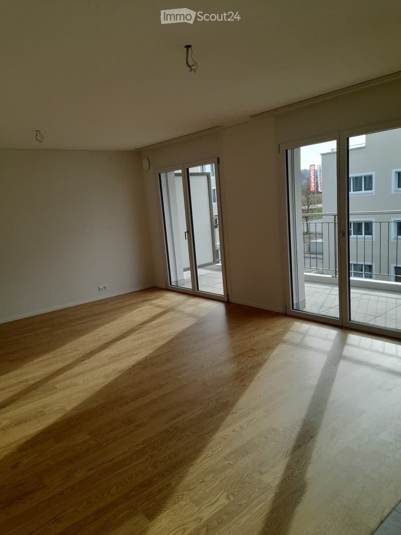 Empty room with wooden flooring and large sliding glass doors leading to a balcony area.