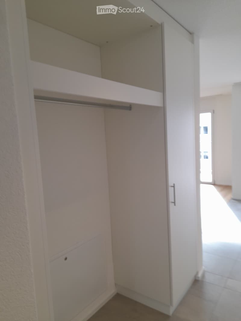 Empty closet with white walls, wooden floor, and built-in storage units including shelves and a hanging rod.