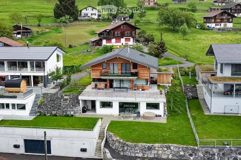 Aerial view of a residential area with multiple houses, green lawns, and a well-maintained garden.
