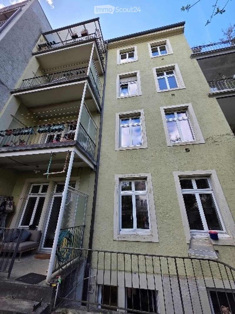 Multi-story residential building with multiple balconies and windows, featuring a mix of modern and traditional architectural elements.