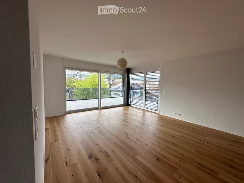 Empty room with wooden flooring, large sliding glass doors, and a hanging light fixture.