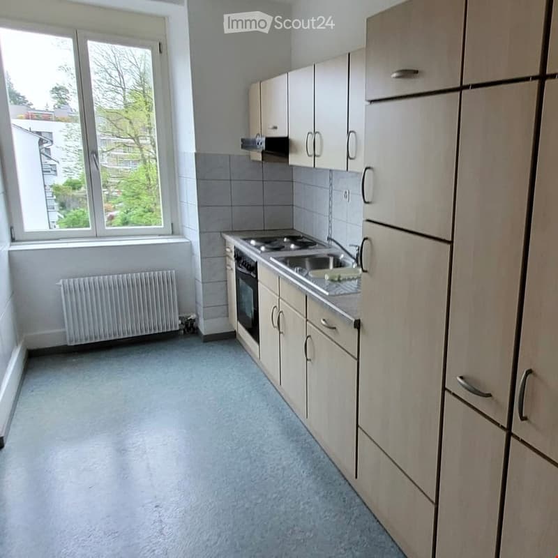 Modern kitchen with light-colored cabinets, a sink, an oven, and a radiator under the window.