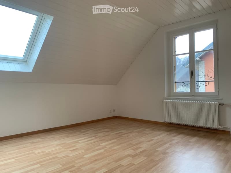 Empty room with wooden flooring, white walls, and two windows, one of which is a skylight. A radiator is visible under one window.