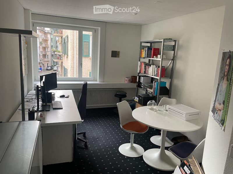 Office space with a desk, chair, round table, bookshelf, and various office supplies.