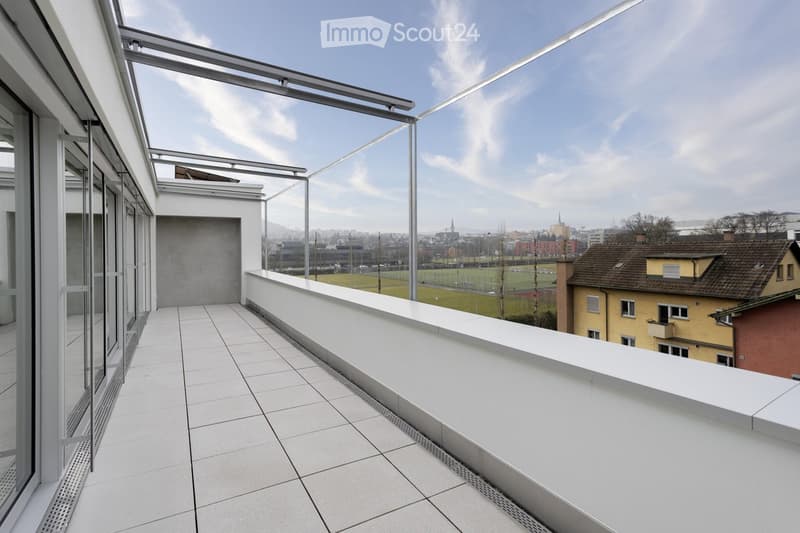Modern balcony with white tiled floor, glass railing, and cityscape view.
