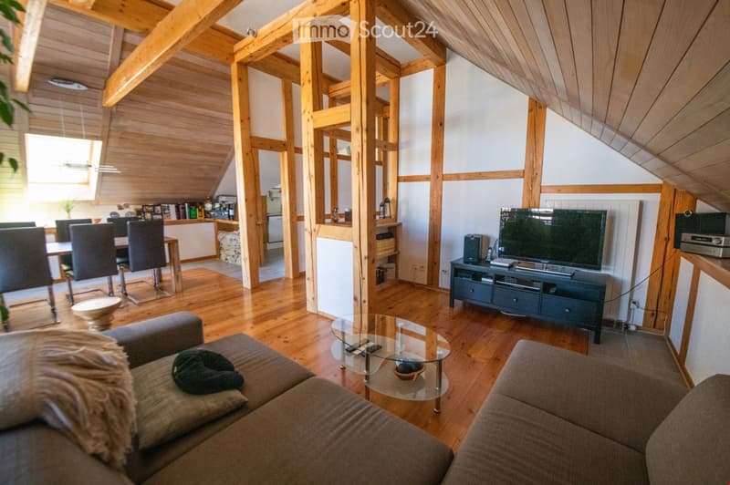 A spacious, open-concept living and dining area with wooden beams and flooring, featuring a sofa, coffee table, television, dining chairs, and a small table.