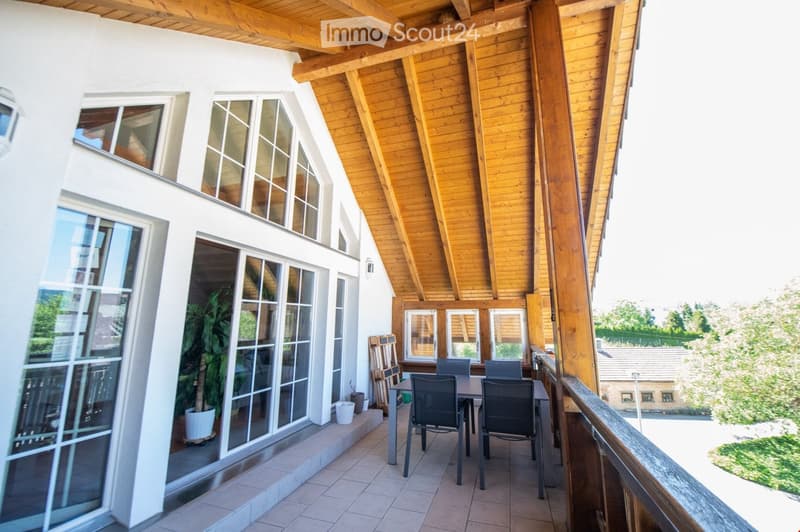 Balcony with wooden ceiling, tiled floor, large windows, and outdoor furniture including a table and chairs.
