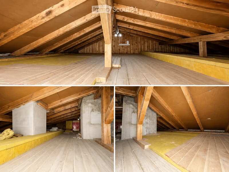 Empty attic space with exposed wooden beams, wooden flooring, insulation, and visible structural supports.