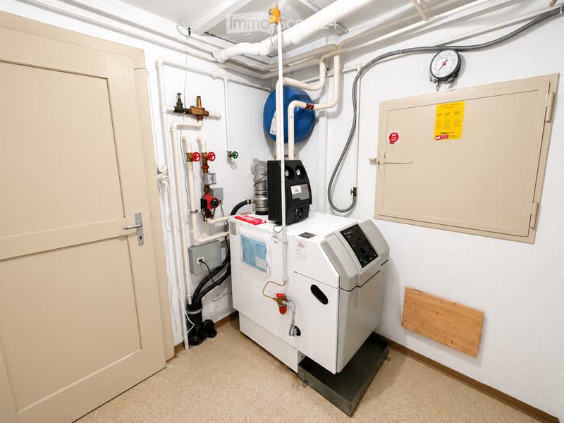 Utility room with a water heater, pressure gauge, electrical panel, and various valves and pipes.