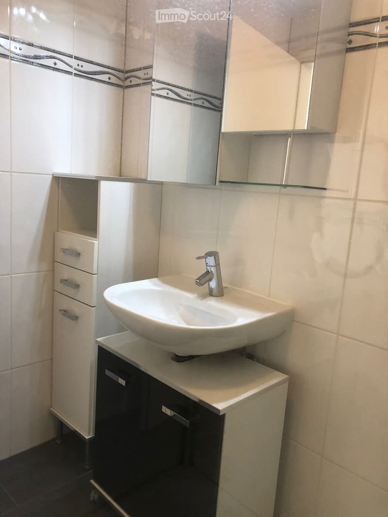 Modern bathroom with a white sink, chrome faucet, mirrored cabinet, and storage drawers.