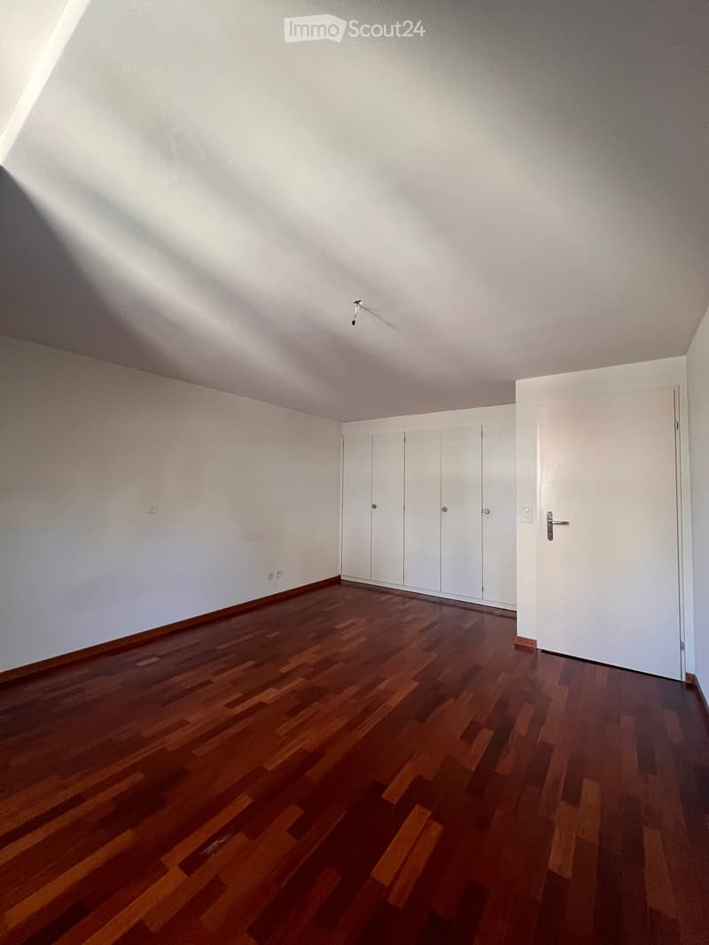Empty room with wooden flooring, white walls, and built-in closet doors.