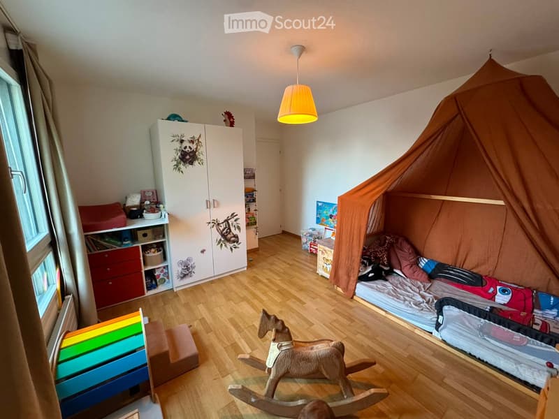 Child's bedroom with a bed under a tent, a rocking horse, a colorful storage unit, and a white wardrobe with animal decals.