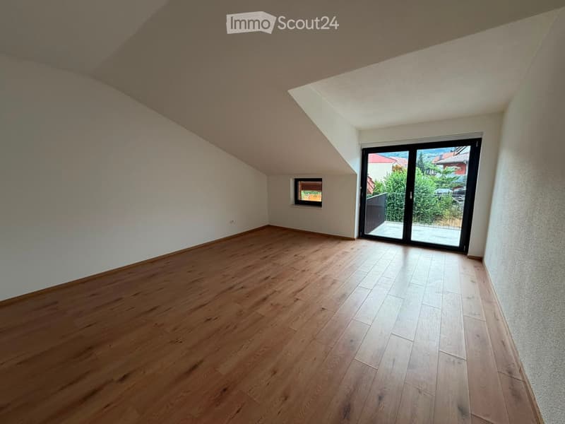 Empty room with wooden flooring, white walls, and large sliding glass door leading to a balcony.