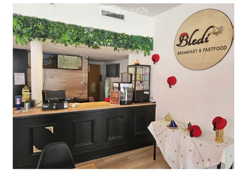 Breakfast and fastfood counter with a cash register, refrigerator, menu board, and a small table with decorative items.