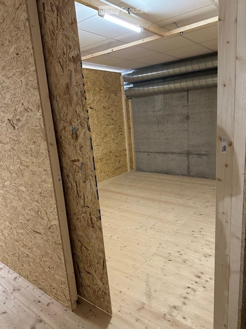 Empty room with wooden flooring, exposed wooden walls, and visible metal ductwork in the ceiling area.