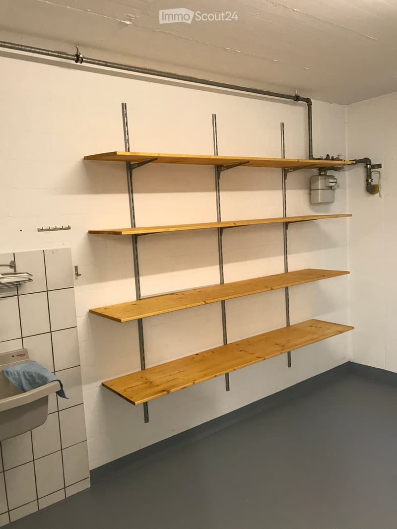 Bathroom with white brick walls, wooden shelves mounted on the wall, a sink with a faucet, and a towel draped over the sink.