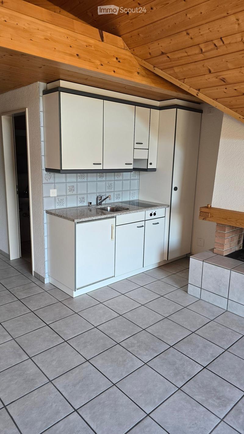 Modern kitchen with white cabinets, granite countertop, and a sink. The room features a tiled backsplash and a wooden ceiling.