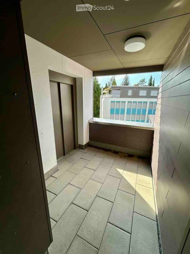 Balcony with tiled floor, white walls, and a view of a neighboring building with a balcony and railing.