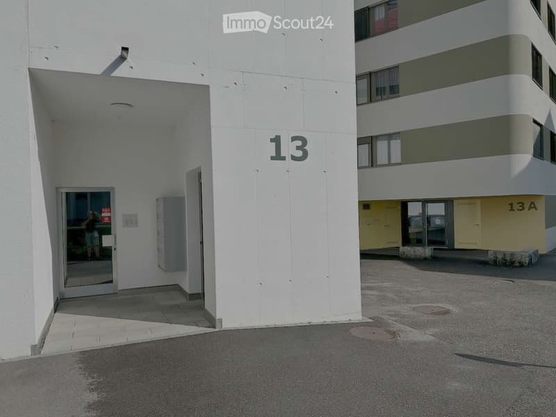Exterior view of a modern multi-story building with white walls and numbered entrances, including unit13 and 13A.