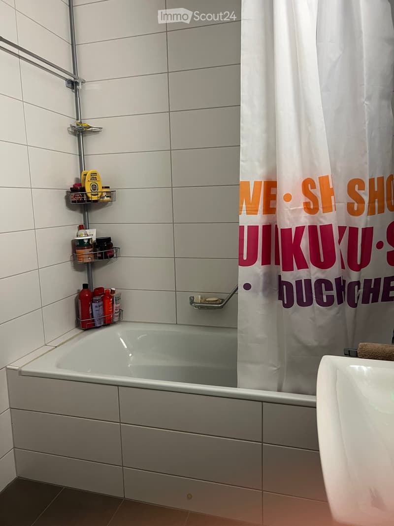 Modern bathroom with a bathtub, shower curtain, and multiple shelves holding toiletries.