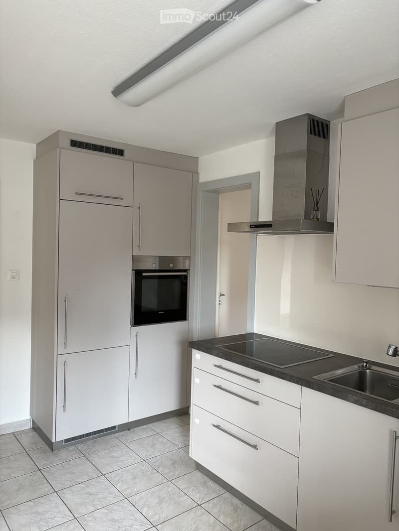 Modern kitchen with white cabinets, stainless steel appliances, and a black countertop.