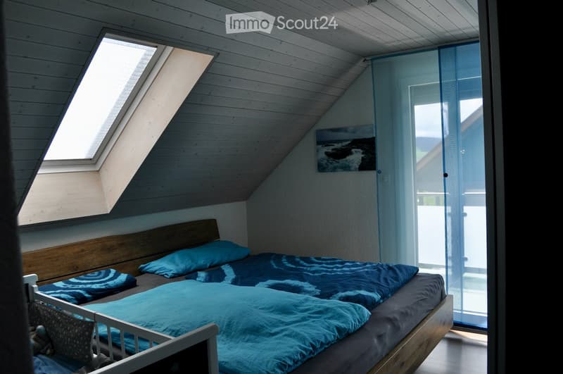 bedroom with wooden bed, blue bedding, wooden headboard, skylight, balcony