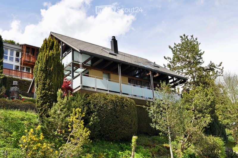 modern house, glass balcony, gray roof, surrounded by trees and bushes